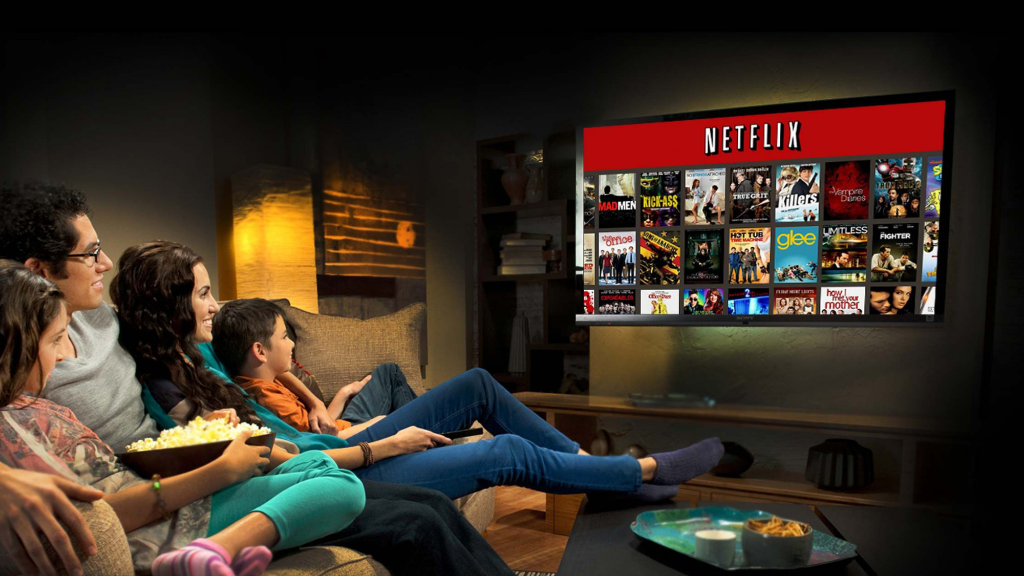 Family watching movies on Netflix with popcorn and snacks.